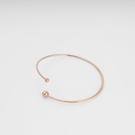 Minimal open 14k gold bangle bracelet with ball ends on white background, simple cuff Ukrainian Jewelry for everyday wear.