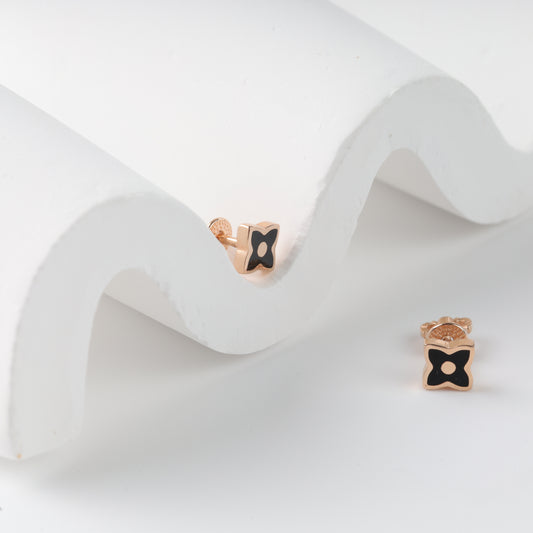 Elegant 14K (585) Rose Gold and black clover studs on a modern white textured background, showcasing their dainty and neat size.