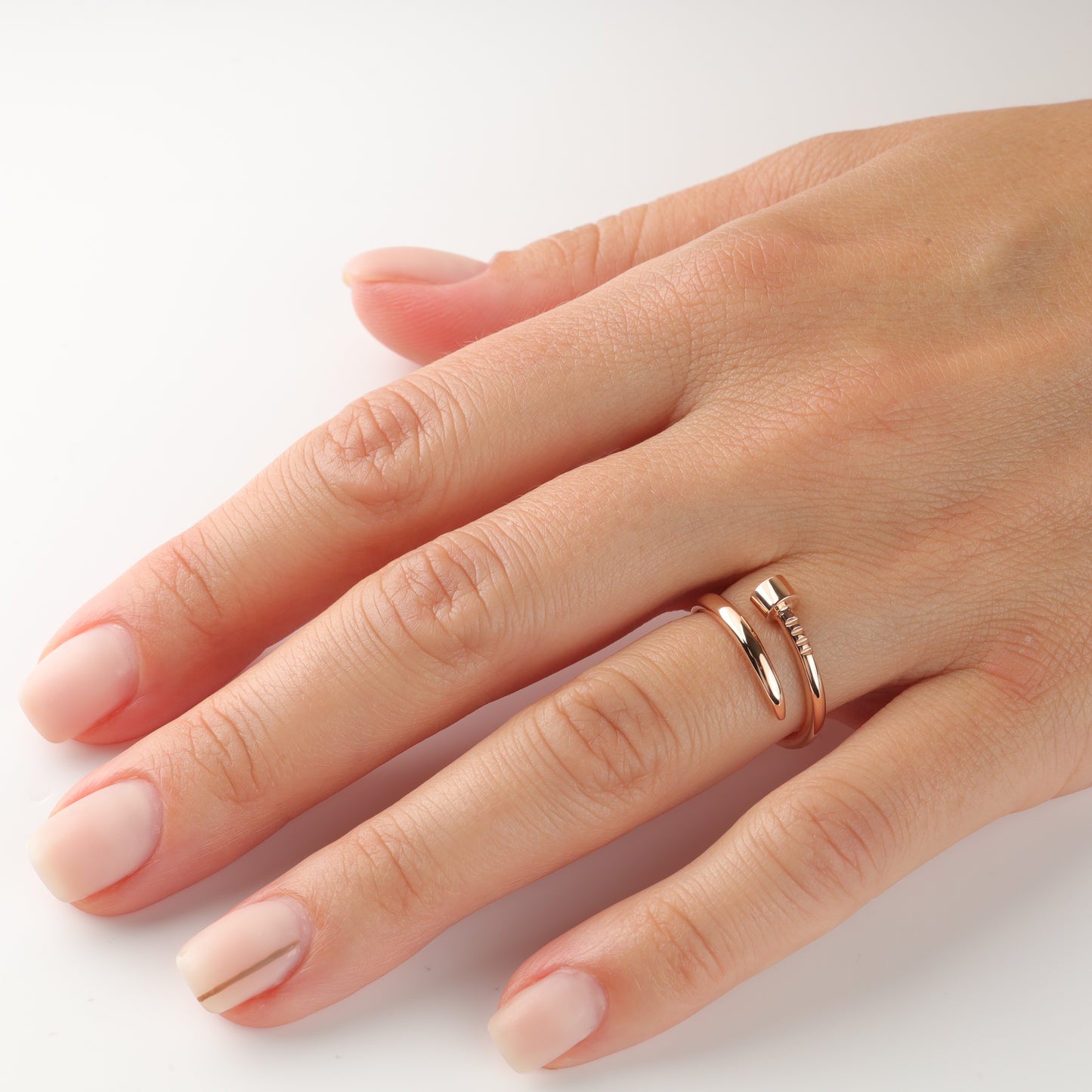 Hand wearing Rose Gold 14K (585) Nail Ring without inserts on a light gray background