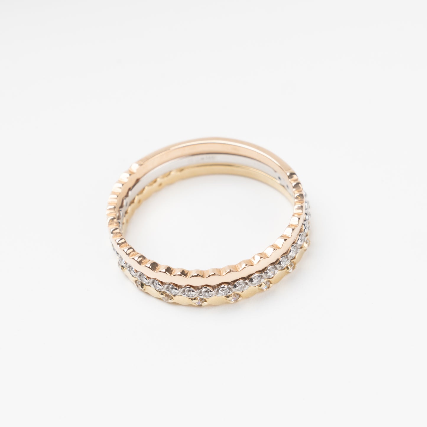 Sophisticated triple stackable ring set in 14K (585) multi-tone gold, featuring a central eternity band of clear zirconias White Gold between two uniquely scalloped Rose and Yellow Gold bands, displayed on a clean white background.