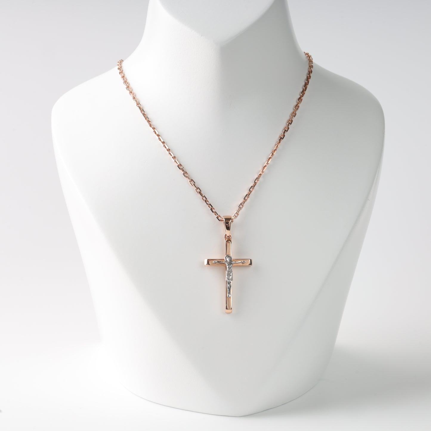 Rose gold cross necklace on a mannequin with a white background