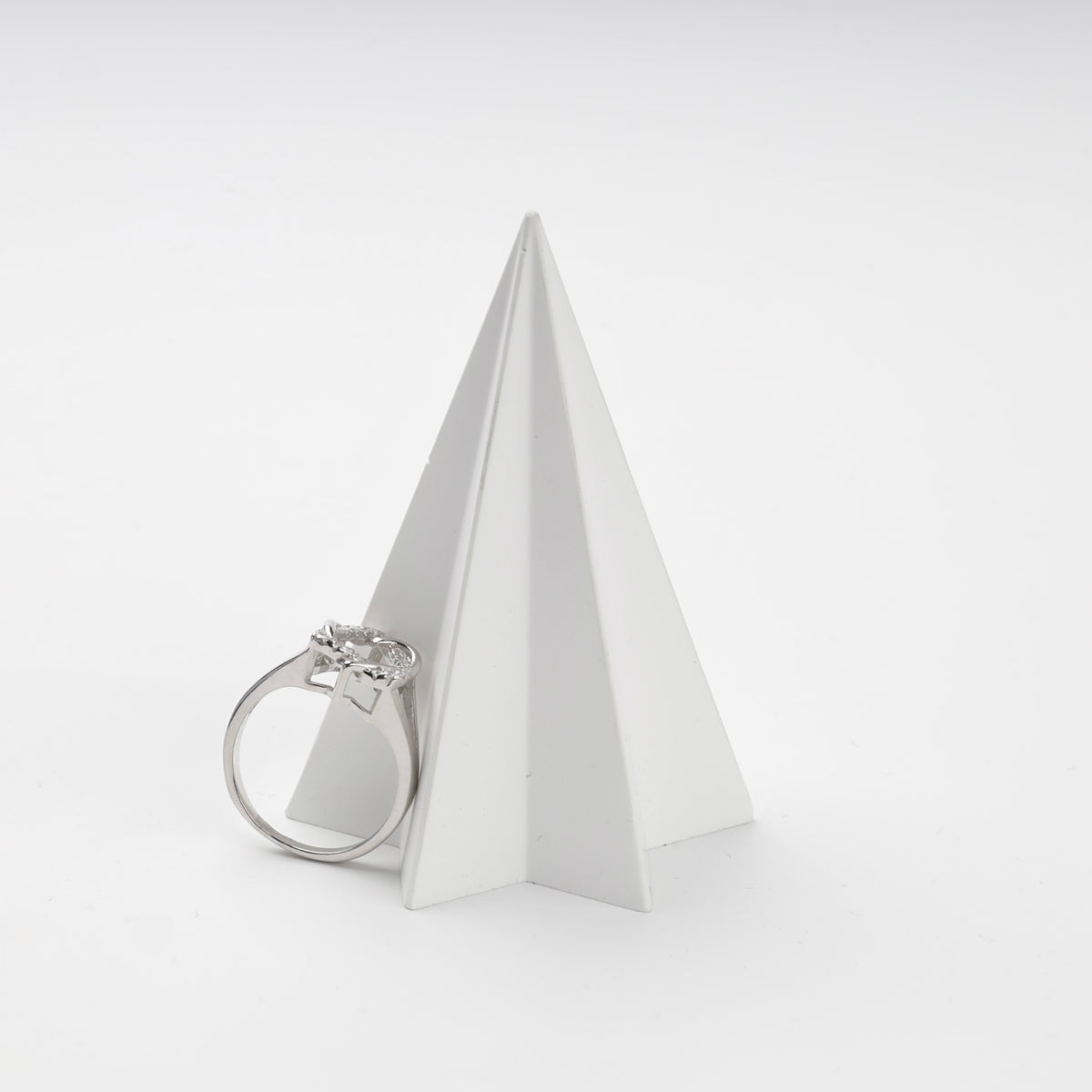 Silver cubic zirconia ring displayed beside a white geometric stand