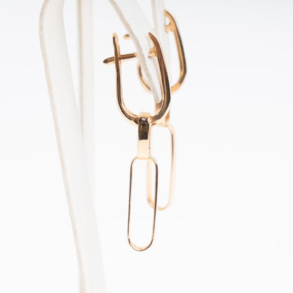 14k gold paperclip dangle earrings on a display stand, minimalist drop hoops, Ukrainian Jewelry for everyday wear.