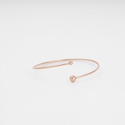 Minimalist 14k gold open bangle bracelet with two ball ends on white background, modern Ukrainian Jewelry for everyday stacking.