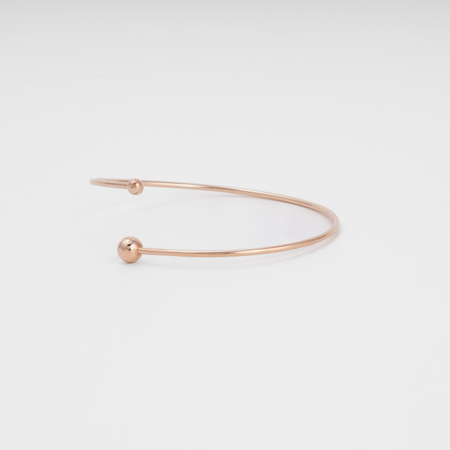 Minimalist 14k gold open bangle bracelet with round ball ends on white background, Ukrainian Jewelry, simple gold cuff bracelet.