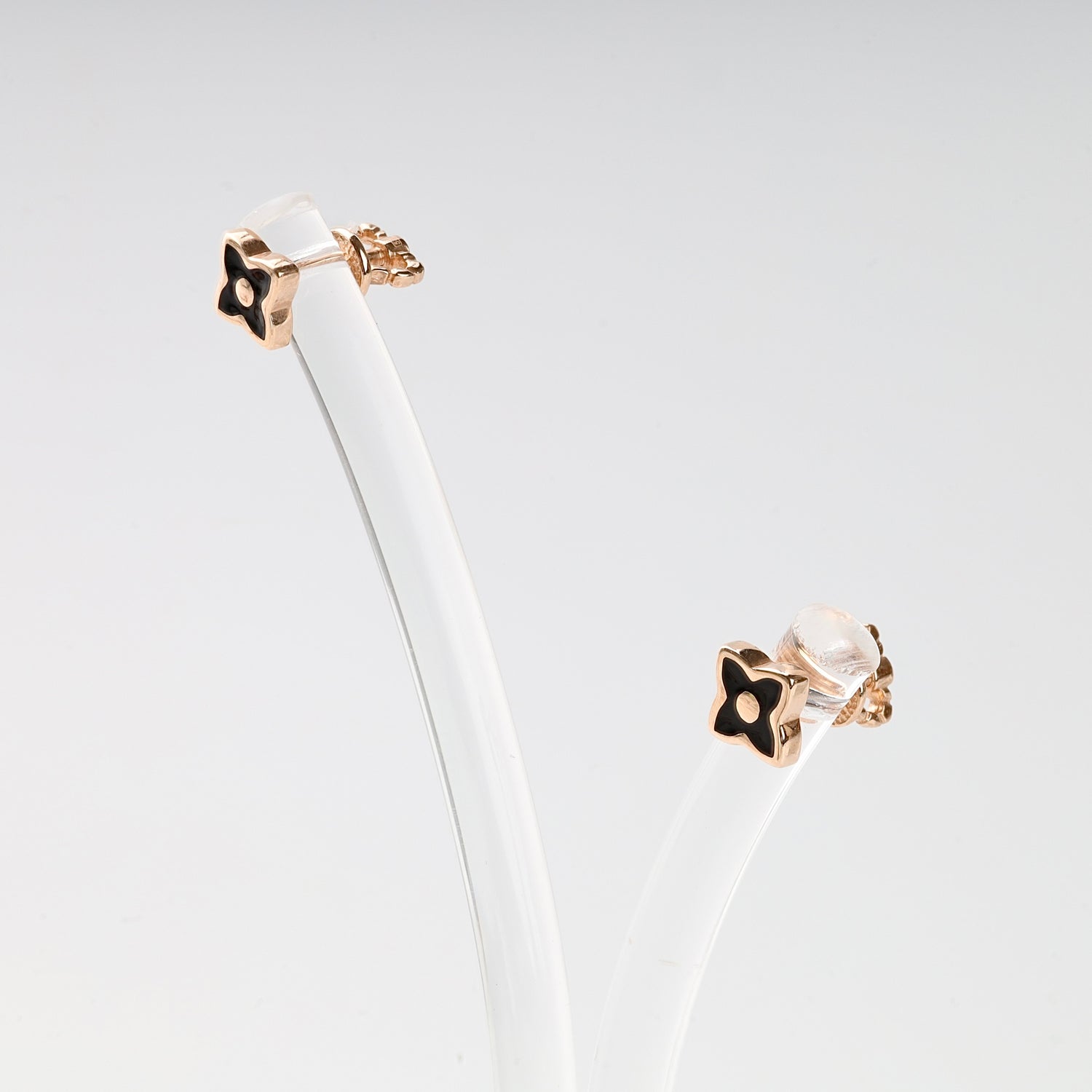 Pair of sophisticated black enamel and Rose Gold 14K (585) flower stud earrings presented on a minimalist jewelry stand.