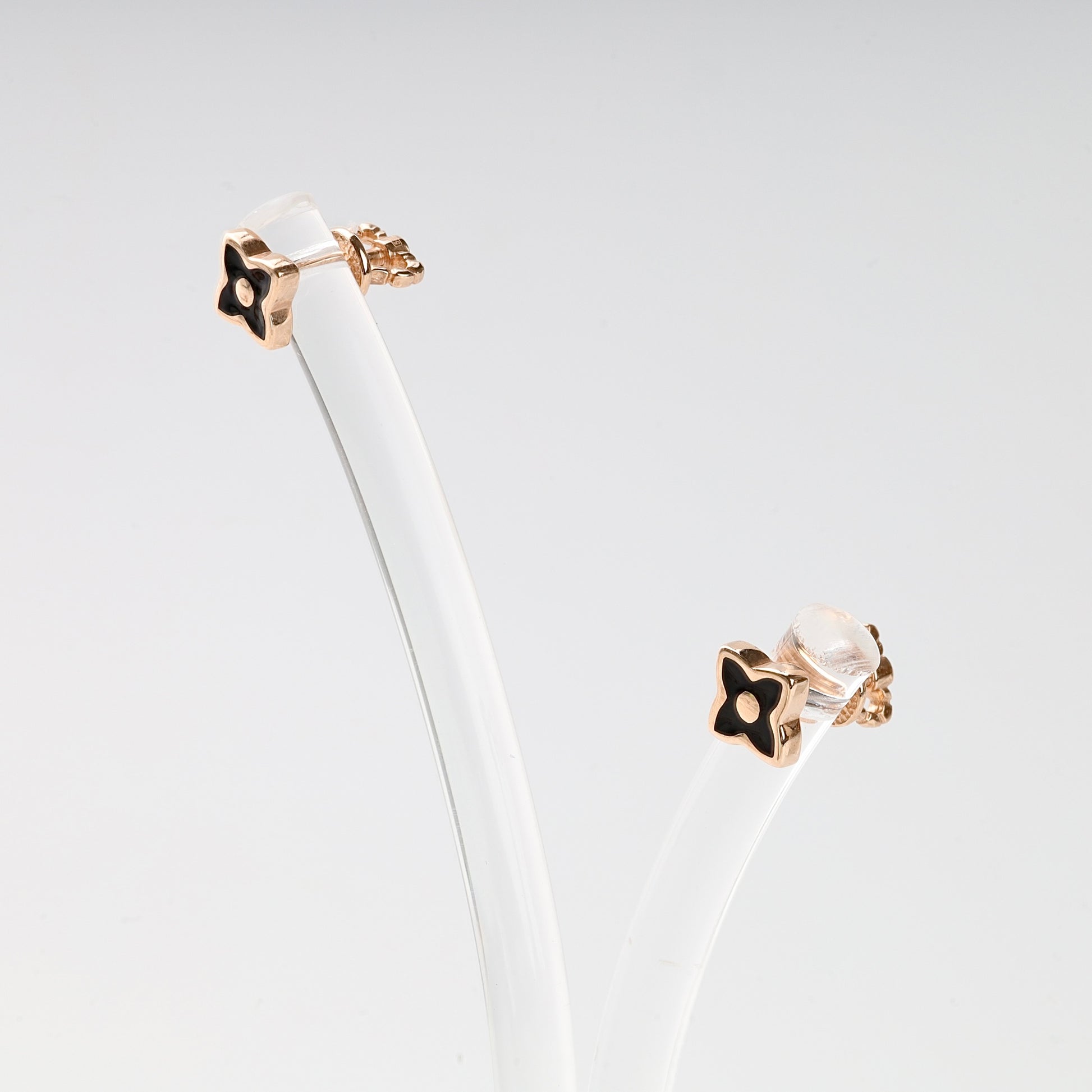 Pair of sophisticated black enamel and Rose Gold 14K (585) flower stud earrings presented on a minimalist jewelry stand.
