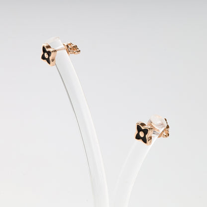 Pair of sophisticated black enamel and Rose Gold 14K (585) flower stud earrings presented on a minimalist jewelry stand.