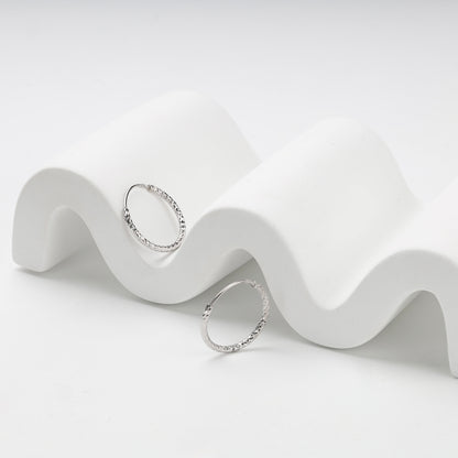 Slim silver hoop earrings with faceted diamond-cut texture