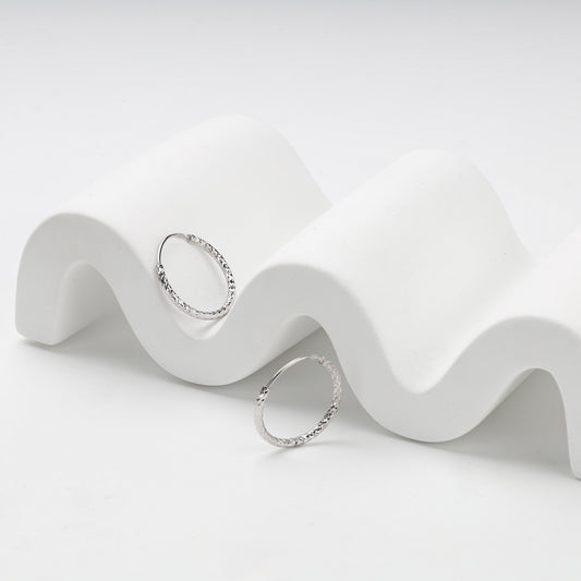 Slim silver hoop earrings with faceted diamond-cut texture