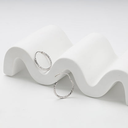 Integrated hinged wire closure on silver hoop earrings