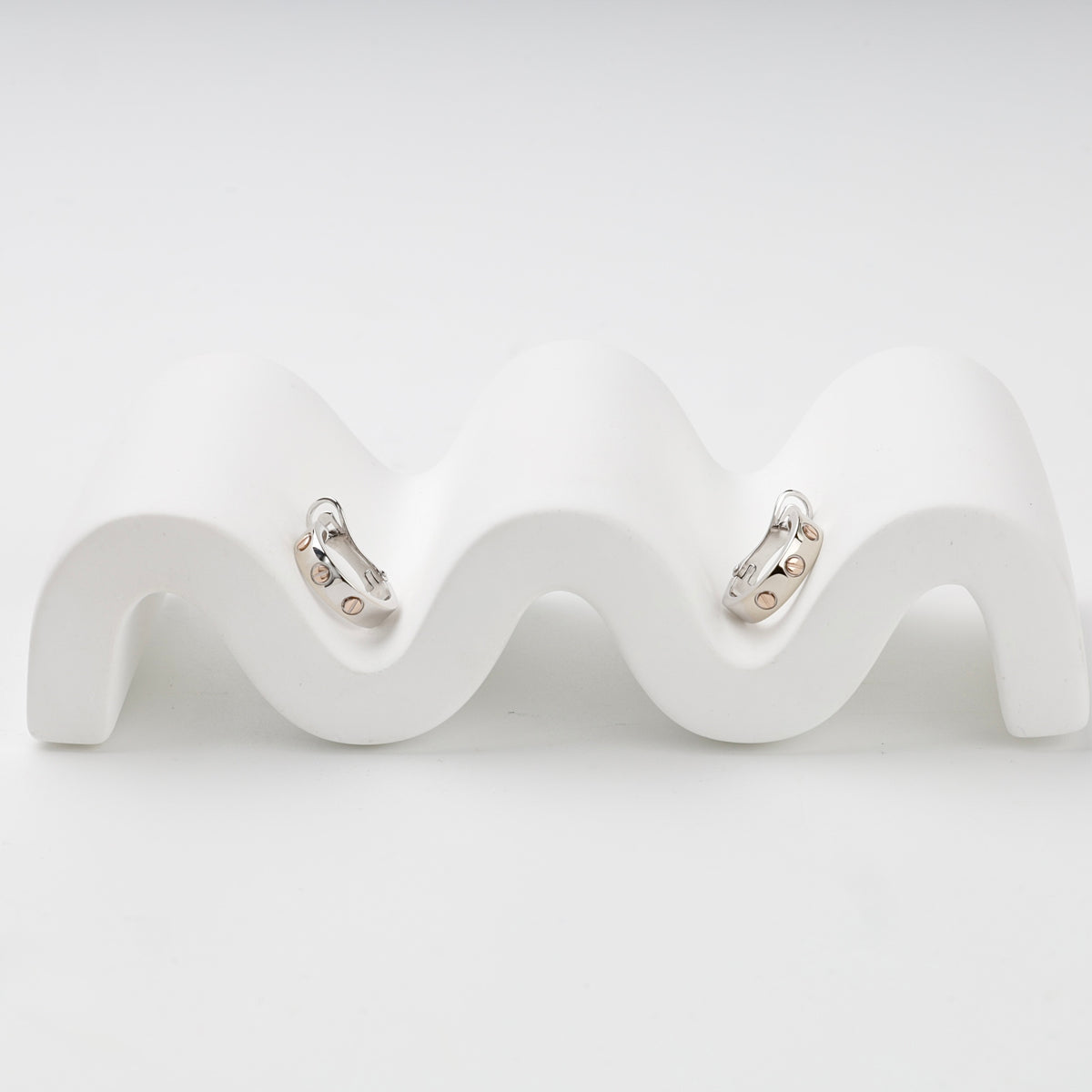 Two-tone gold huggie earrings showing repeating screw details