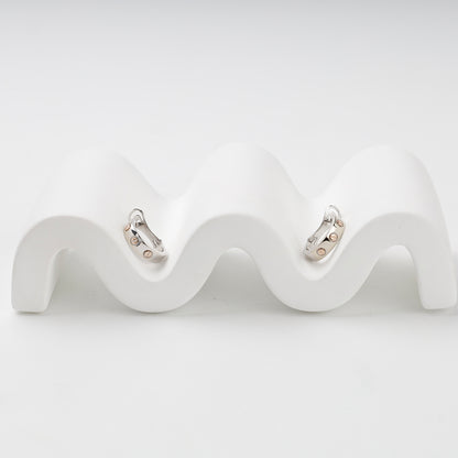 Two-tone gold huggie earrings showing repeating screw details
