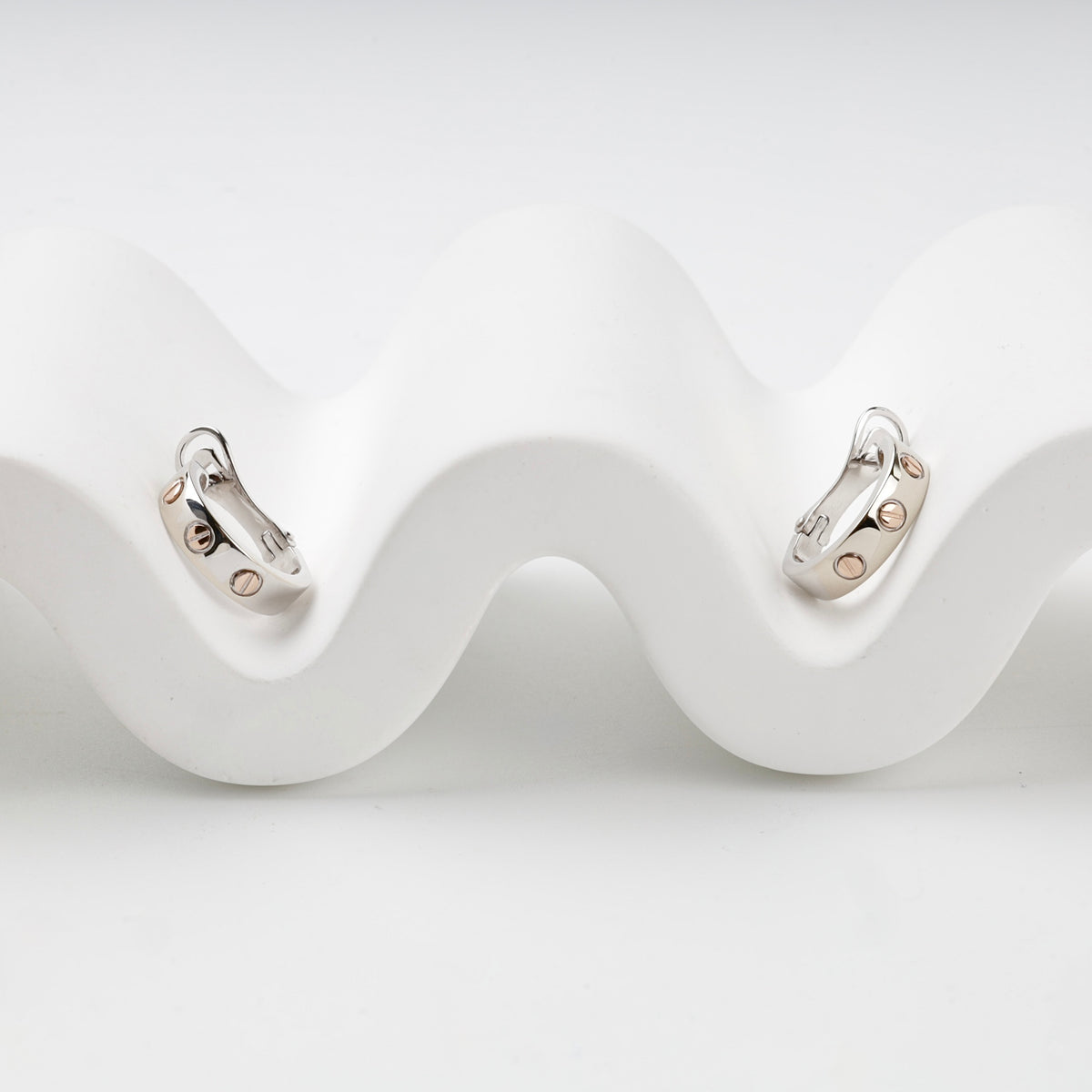 Two-tone 14K gold hoop earrings with rose-gold screw motifs, front view
