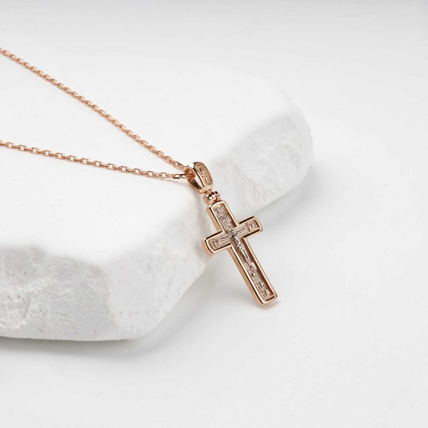 White relief and engraved inscriptions on a gold crucifix pendant