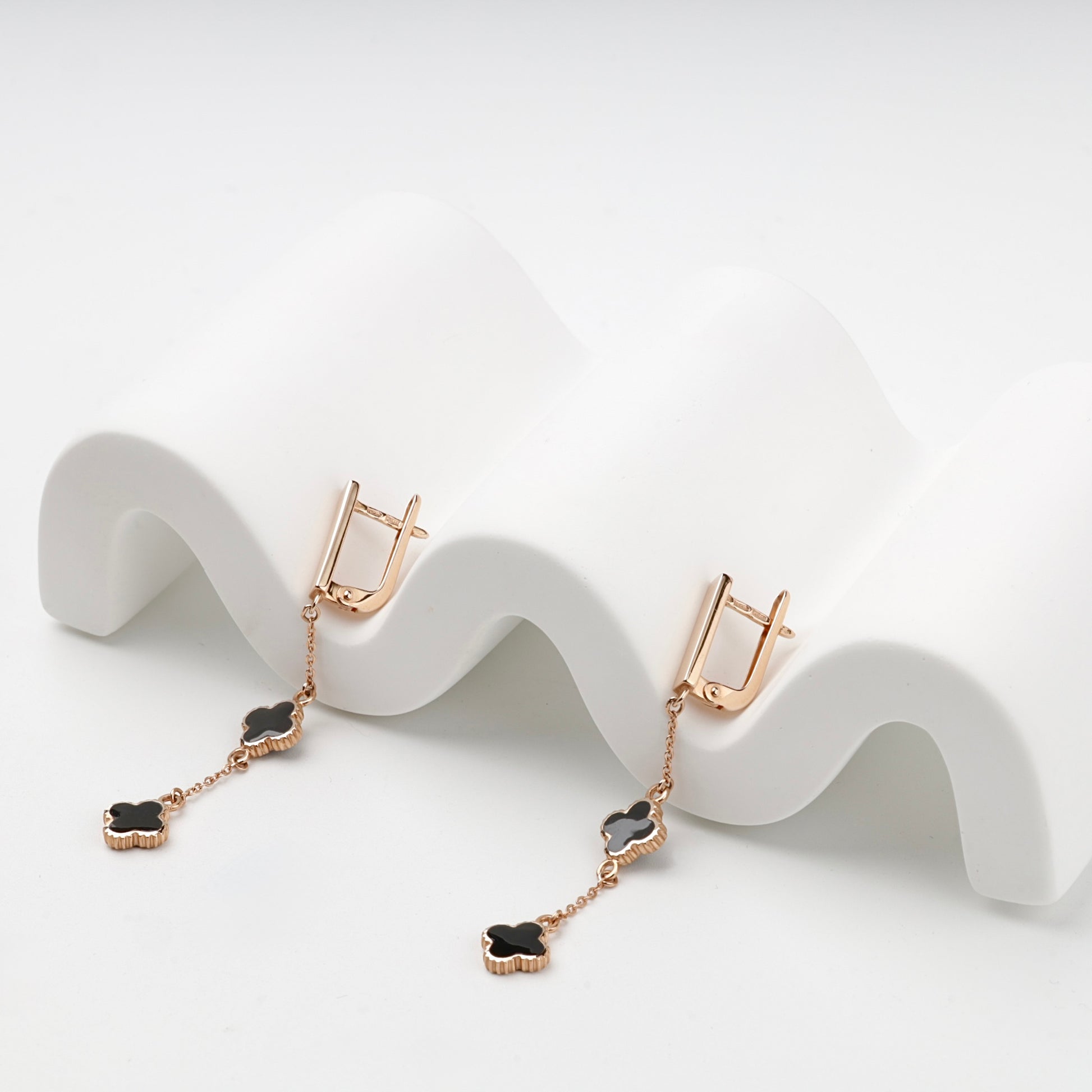 Black enamel clover drop earrings, angled view — Kabluchka
