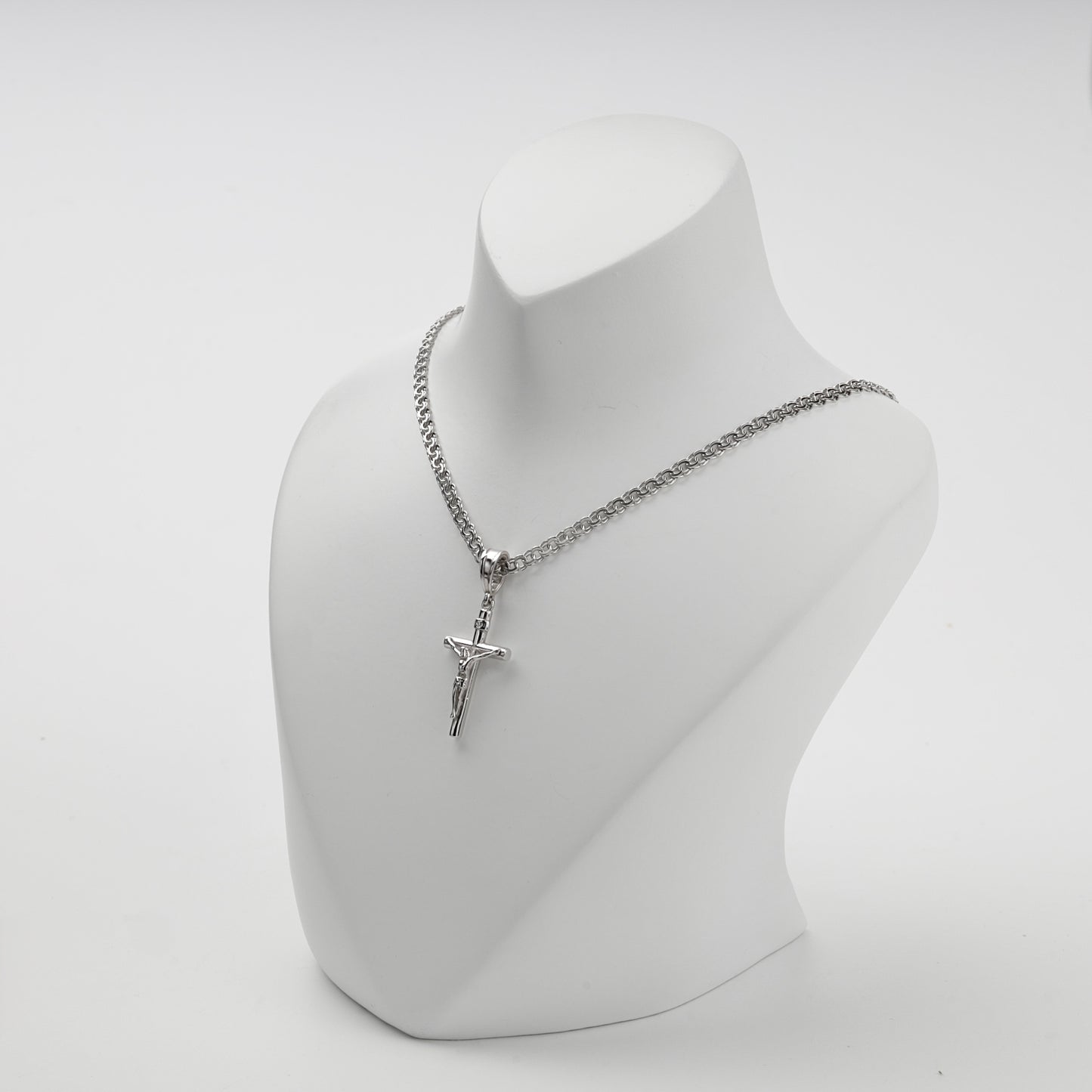 Polished silver crucifix pendant shown at an angle