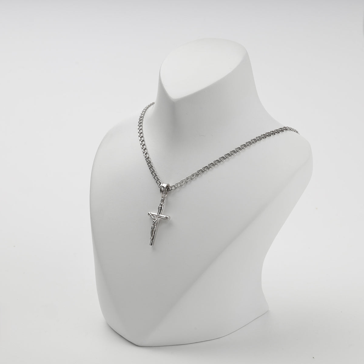 Polished silver crucifix pendant shown at an angle
