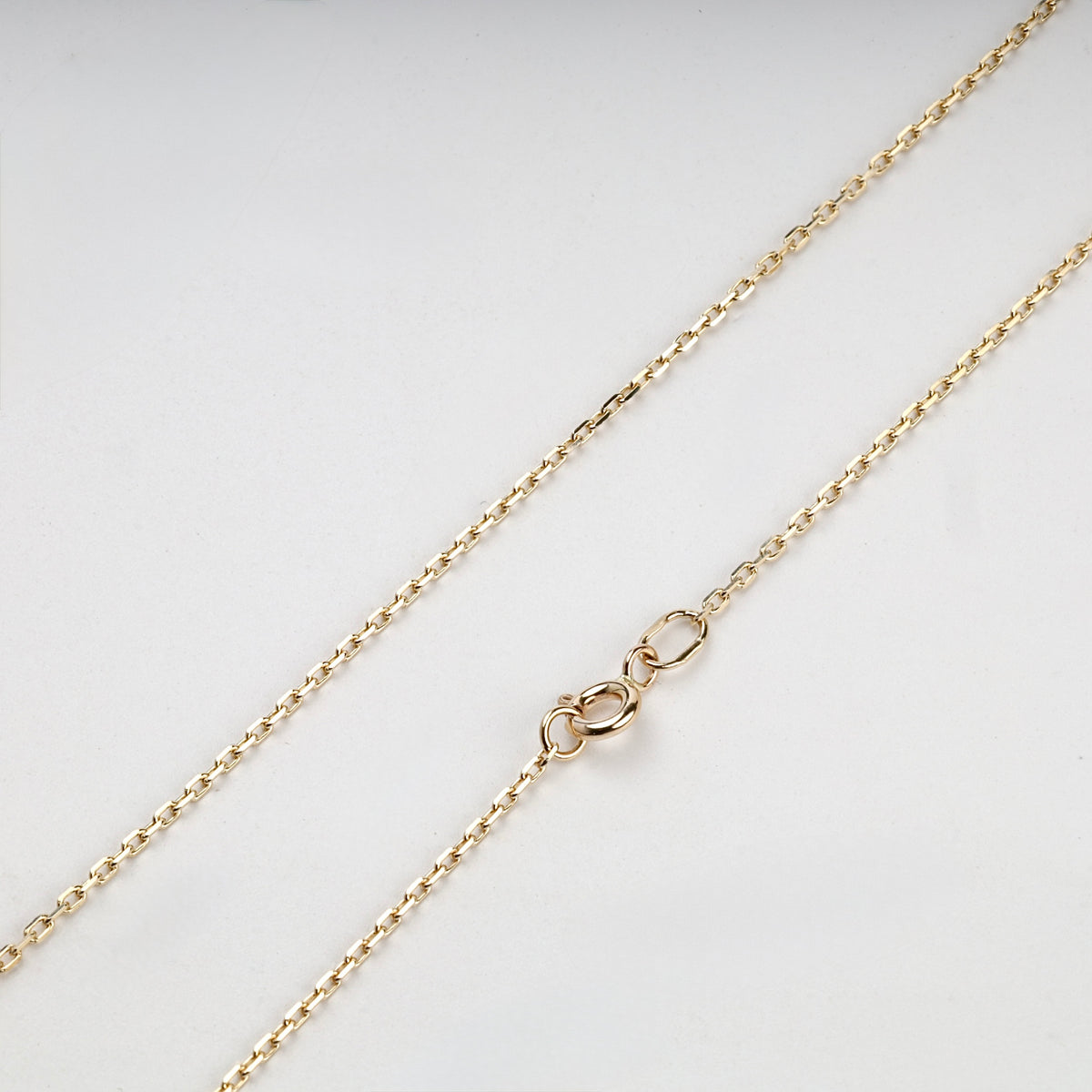 Yellow gold cable chain links and spring ring clasp, close-up