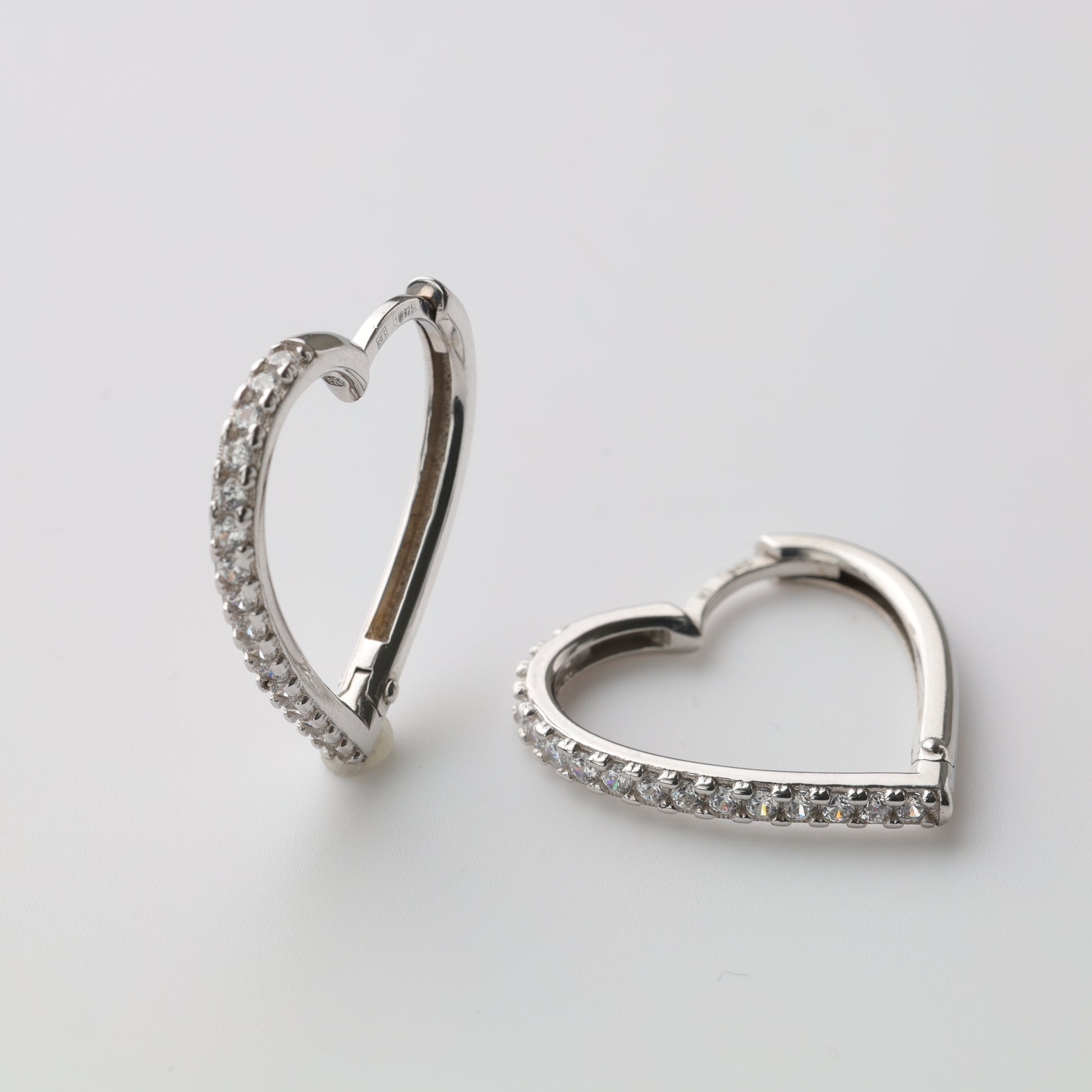 Silver heart-shaped huggie earrings close-up - Kabluchka