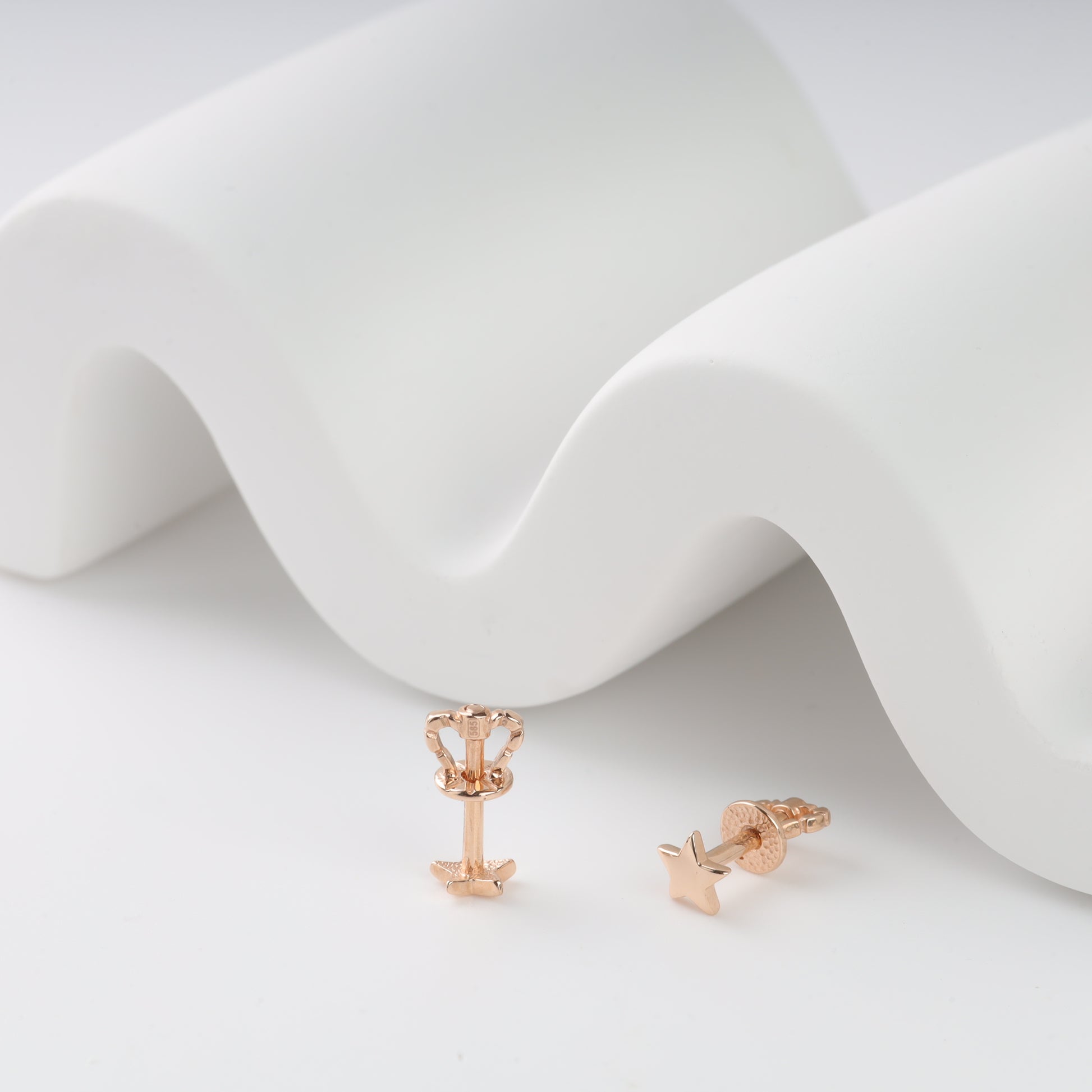 Rose gold earrings on a white fabric background