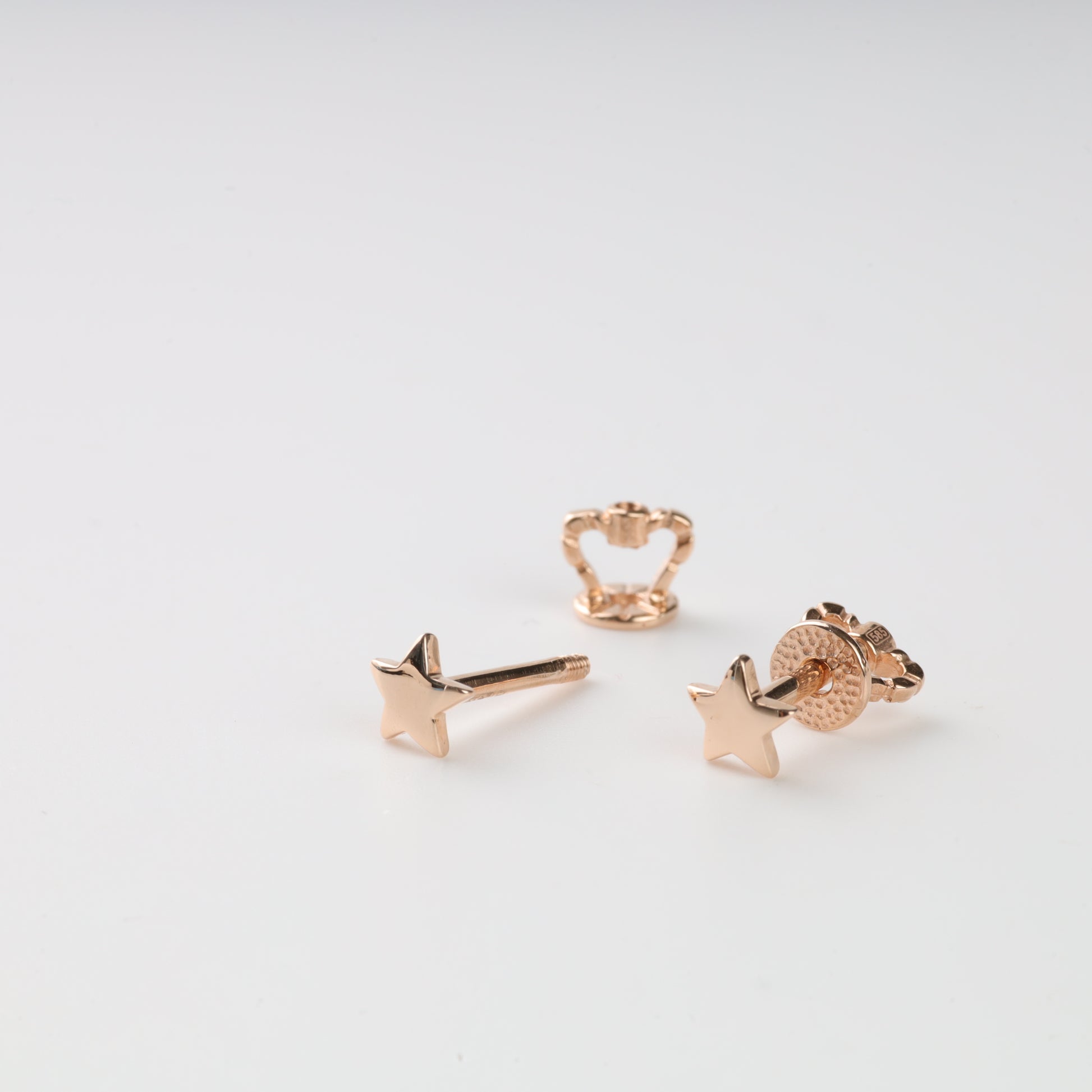 Set of rose gold earrings on a light gray background