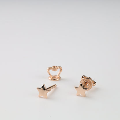 Rose gold star-shaped earrings on a light gray background