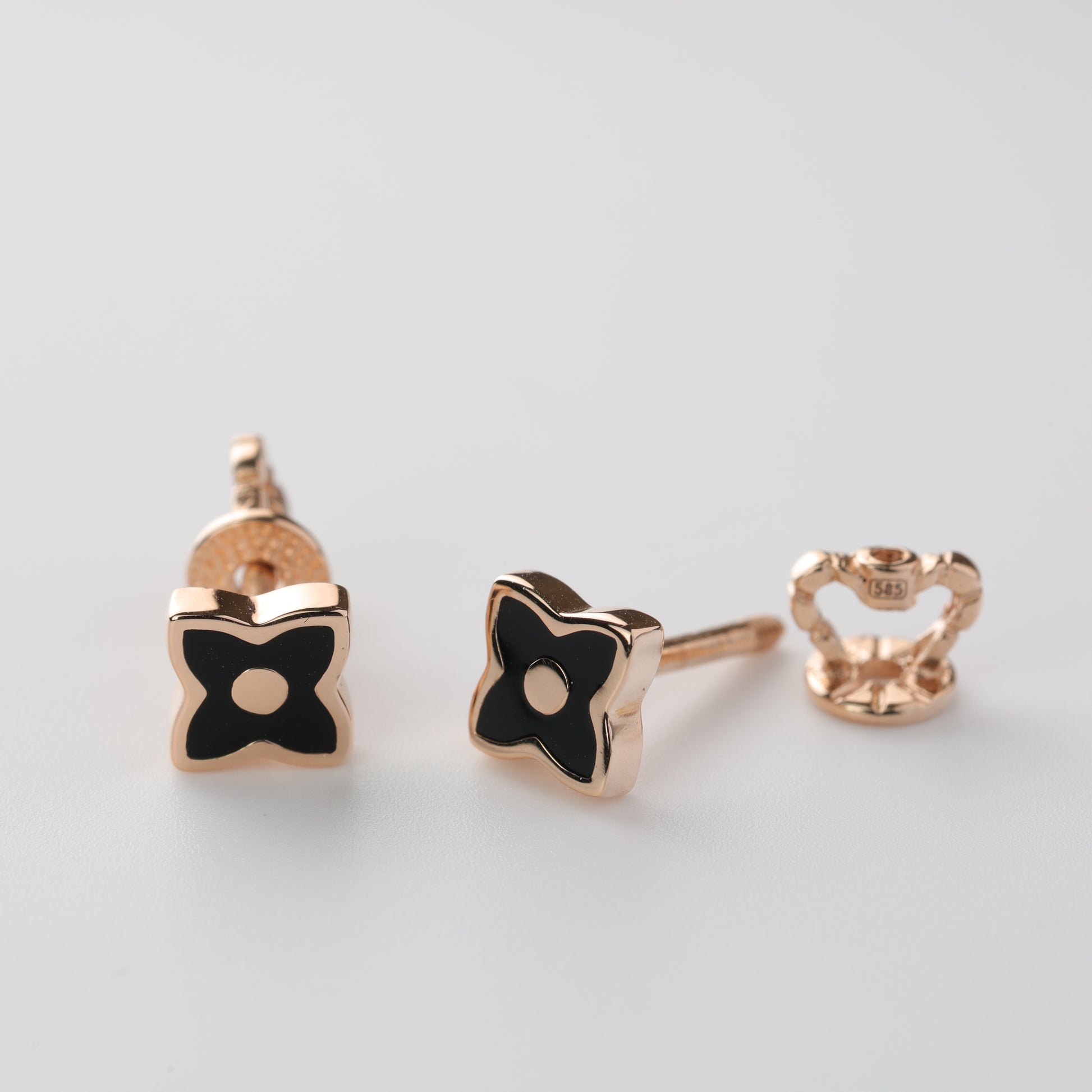 Detailed macro shot of 14K Rose Gold clover earrings with black enamel, showing the 585 hallmark and secure screw-back closure.