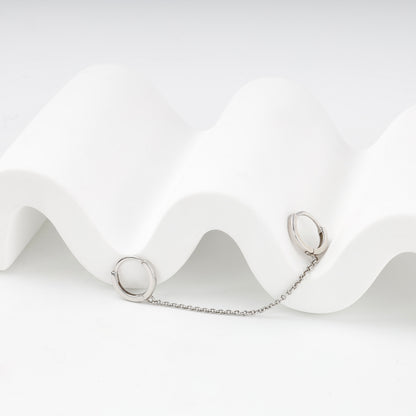 Two small silver huggie hoops connected by a delicate chain — Kabluchka