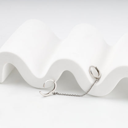 Polished silver huggie hoops joined by a chain, detail — Kabluchka