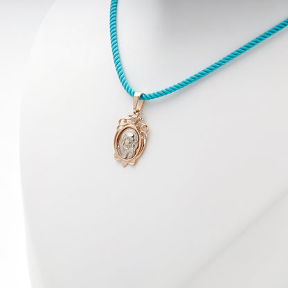 Two-tone gold Virgin Mary and Child pendant on a turquoise styling cord