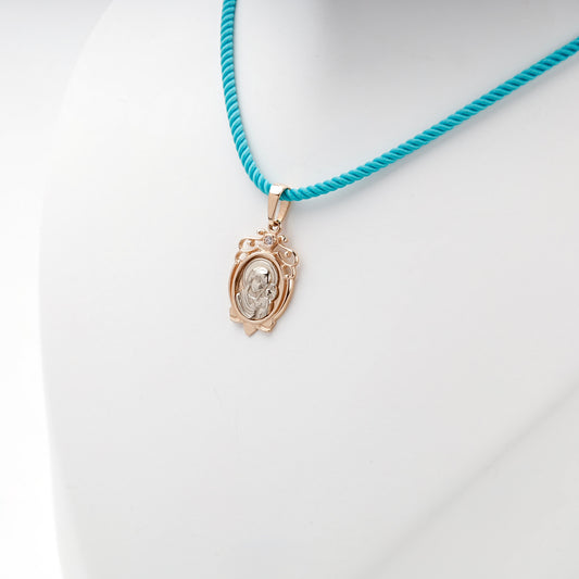Two-tone gold Virgin Mary and Child pendant on a turquoise styling cord
