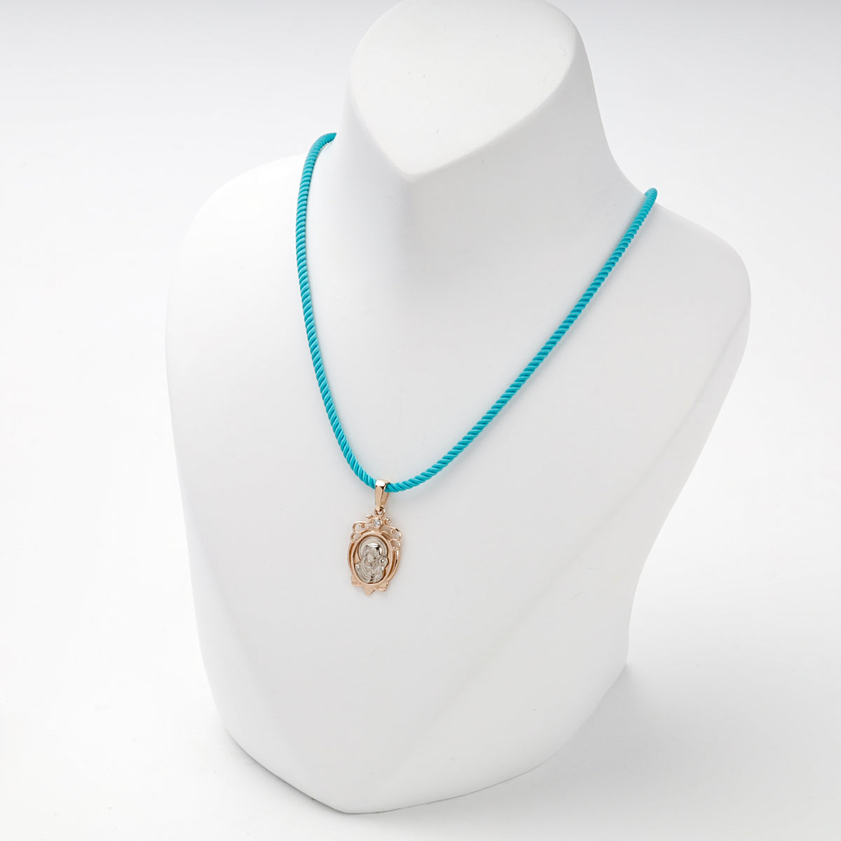 Virgin Mary and Child pendant displayed on a turquoise styling cord