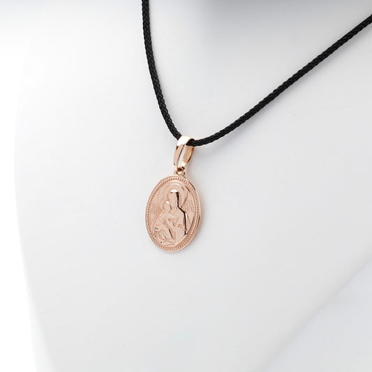 Virgin Mary and Child rose gold pendant shown on a black styling cord