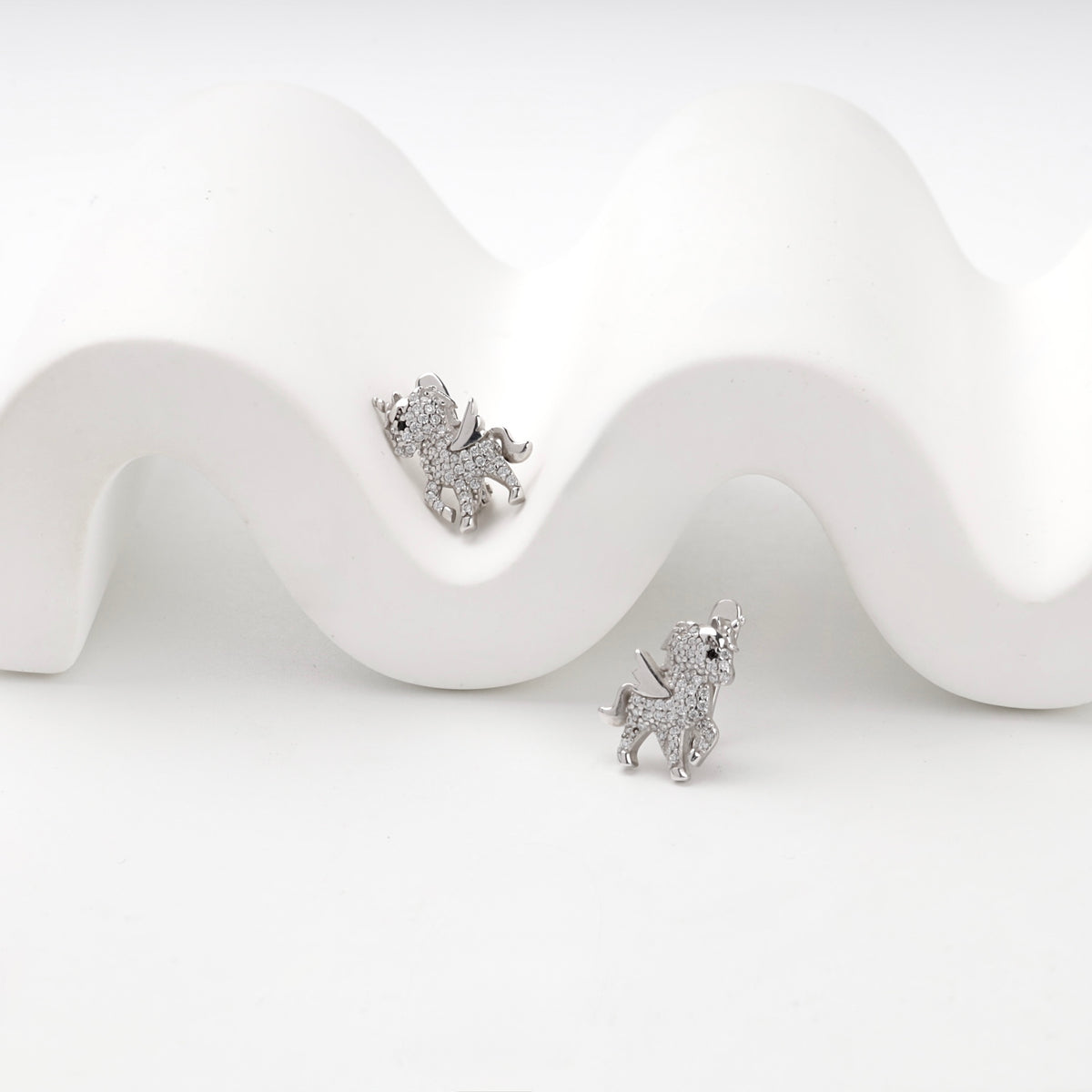 Cubic zirconia winged unicorn earrings, angled view