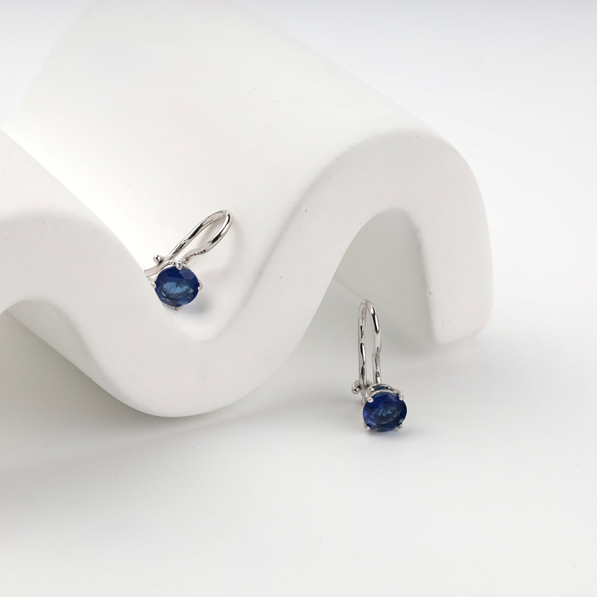 Blue cubic zirconia hook earrings on a white display