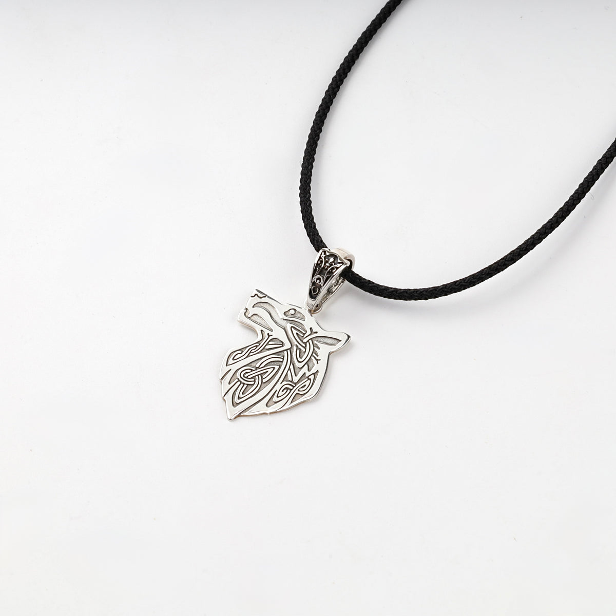 Silver wolf pendant with a decorative bail and dark recessed details