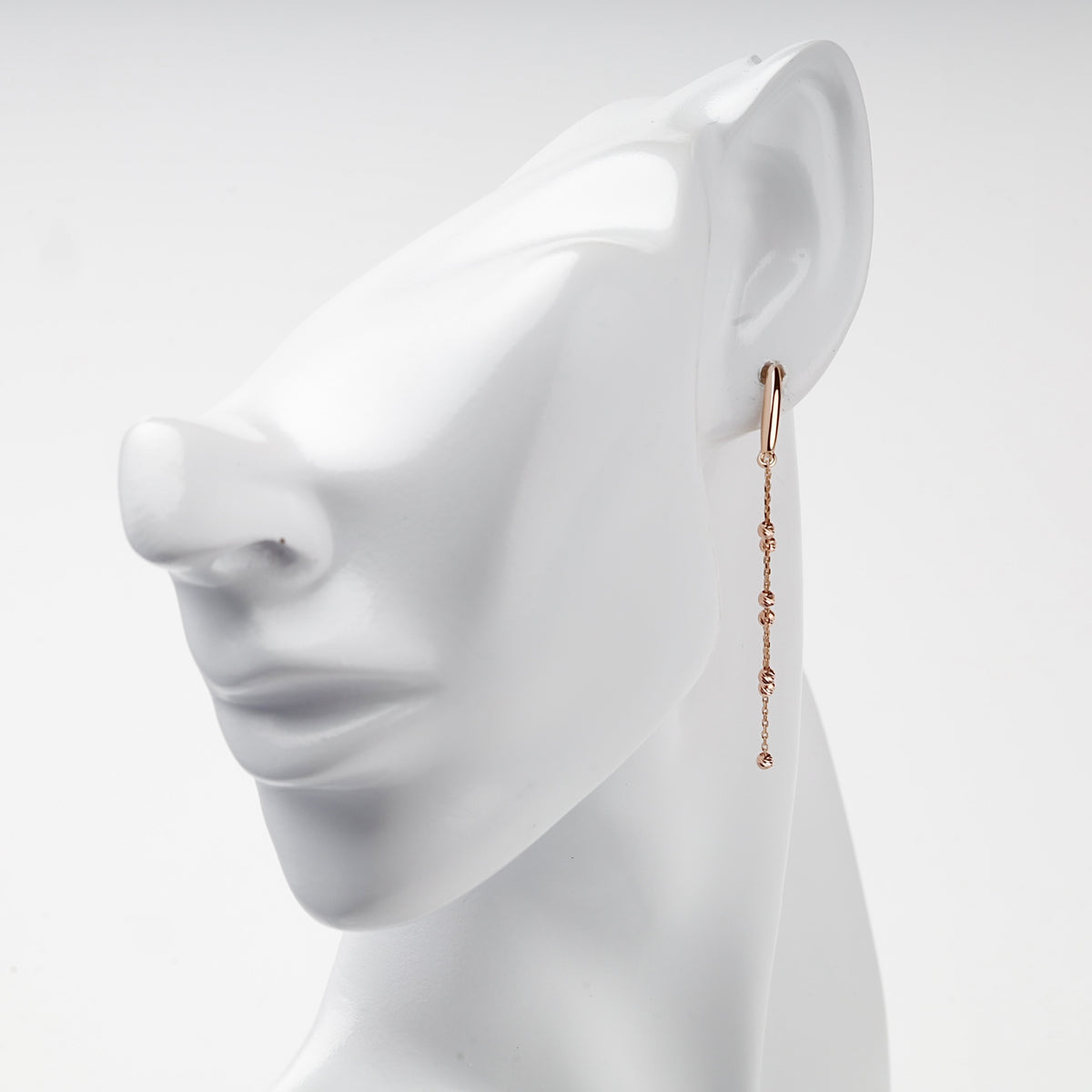 Rose gold 585 beaded chain drop earring worn on ear, side view