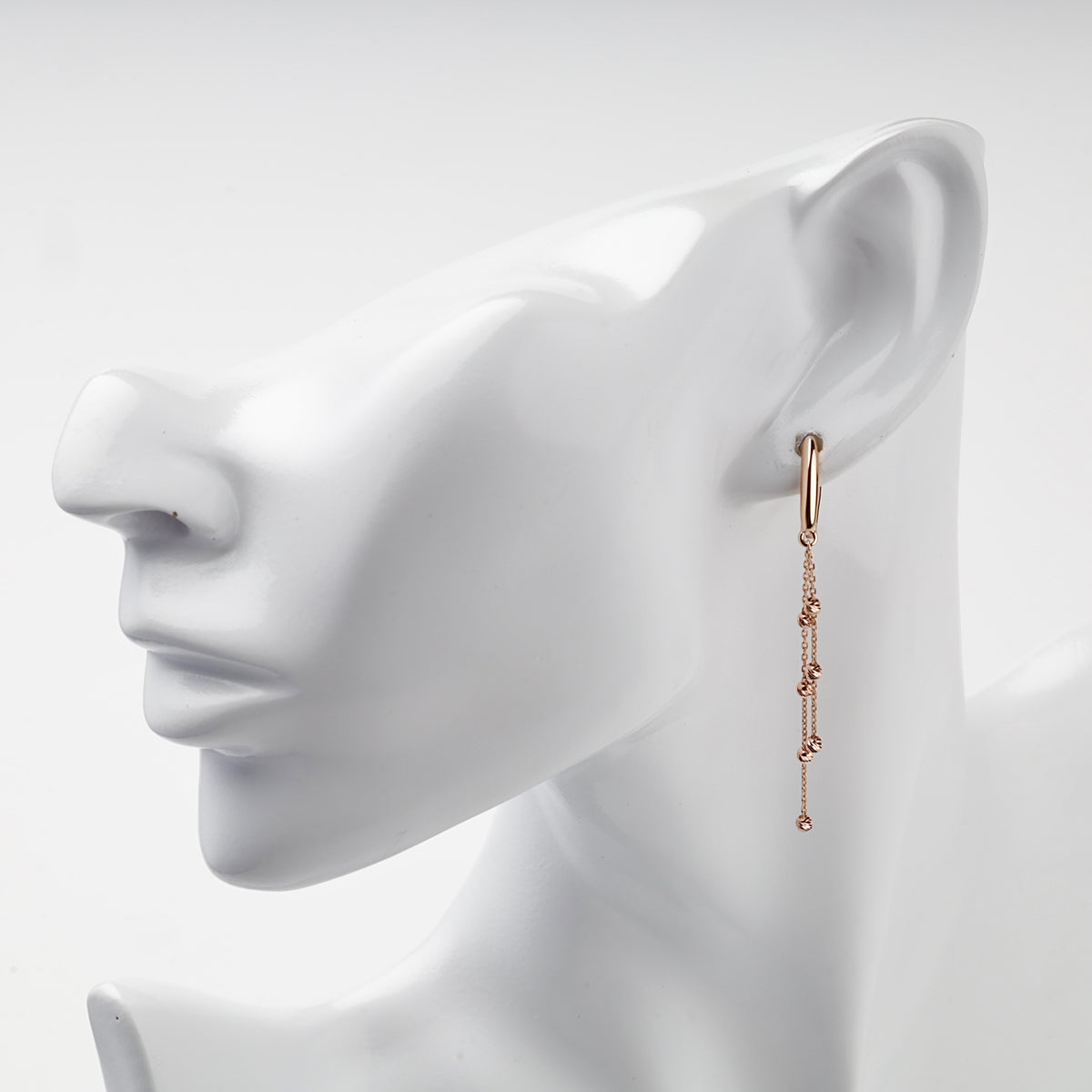 Rose gold 585 beaded chain drop earring worn on ear, front view
