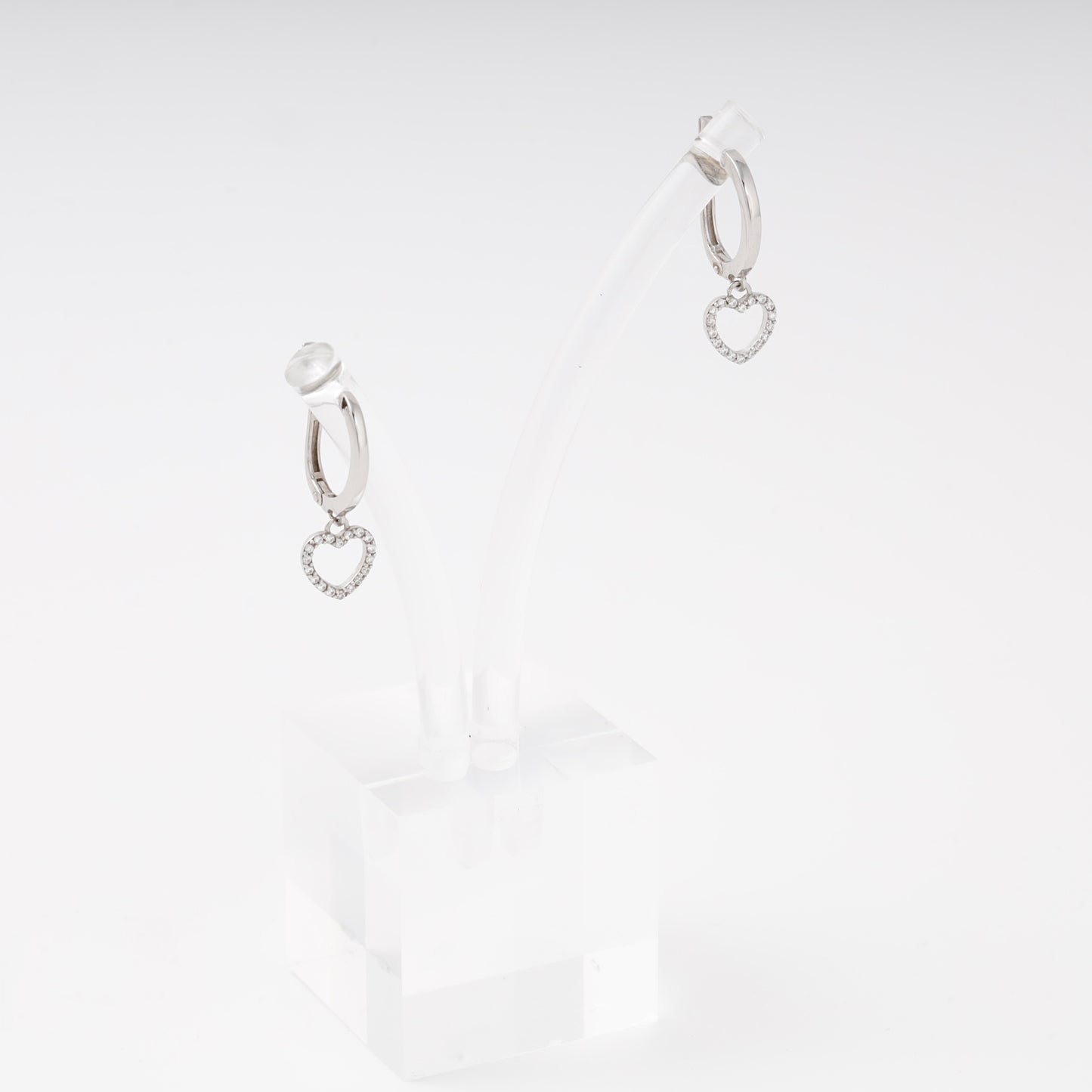 Silver drop earrings with open heart charm and cubic zirconia on display stand, side view — Kabluchka