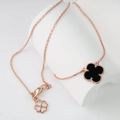 An elegant polished 14K (585) rose gold necklace featuring a delicate chain and a central four-leaf clover pendant. The insert is made of black onyx, framed by a detailed beaded rose gold border.