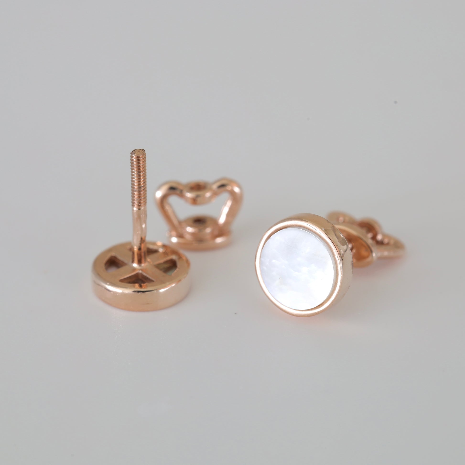 A pair of 14K (585) Rose Gold stud earrings with a secure threaded screw-back mechanism. Each earring holds a shimmering round mother-of-pearl stone in a warm gold frame, displayed on a neutral white background.