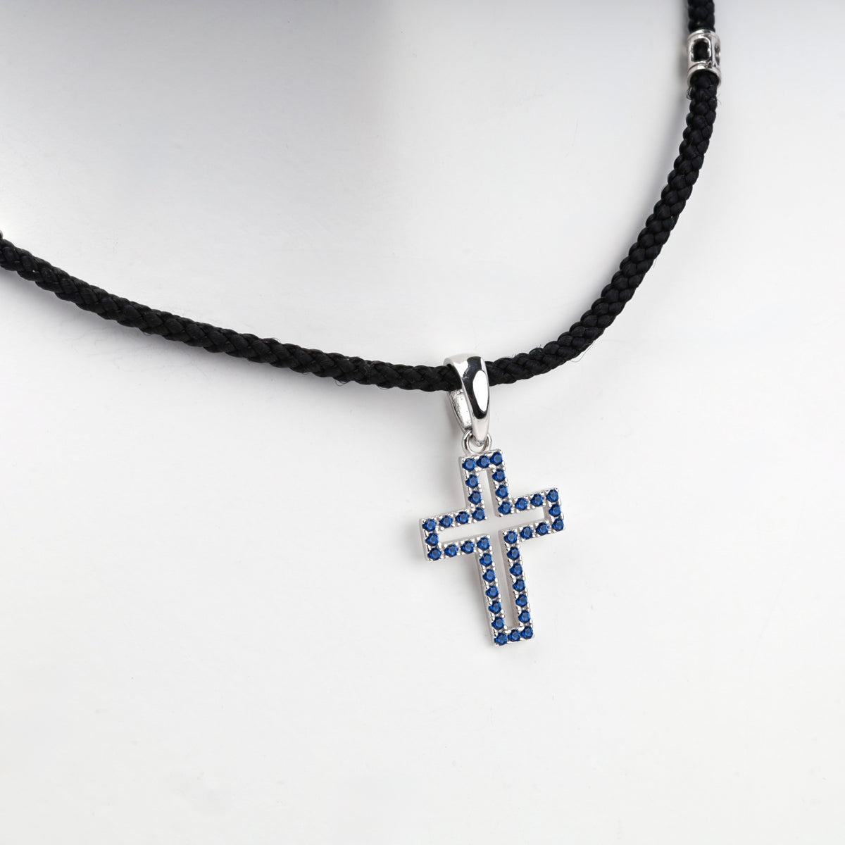 Rhodium-plated silver 925 cross pendant with blue cubic zirconia, angled view
