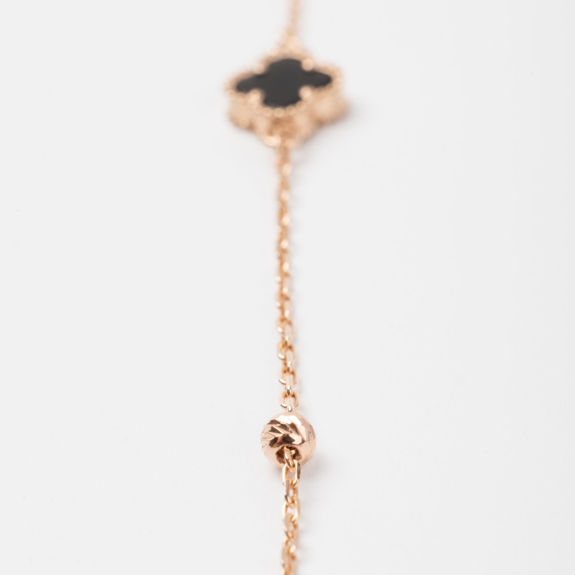 An exquisite 14K (585) Rose Gold bracelet featuring a black four-leaf clover centerpiece accented with four textured, cut-faced gold beads on a delicate chain with an adjustable clasp.