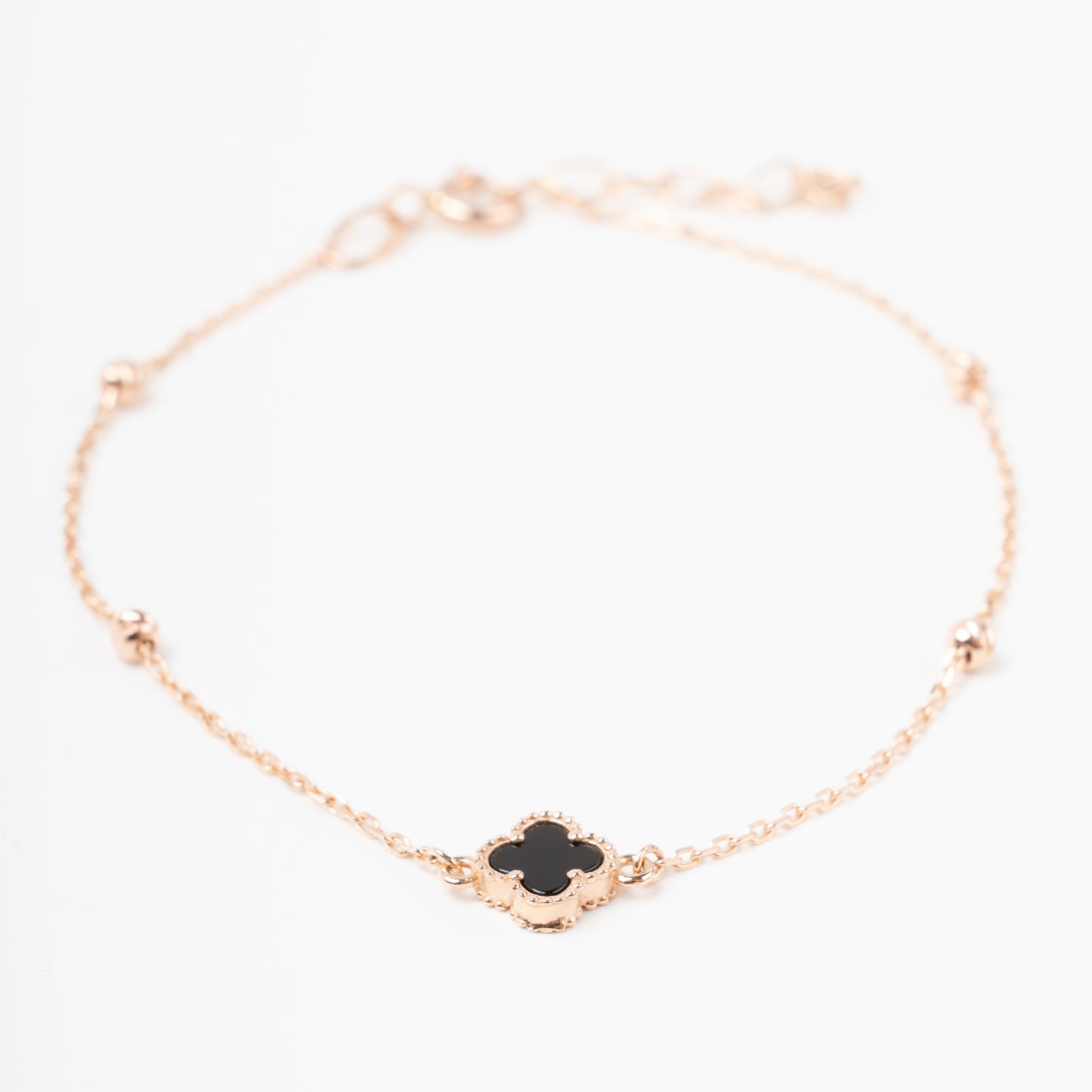 An exquisite 14K (585) Rose Gold bracelet featuring a black four-leaf clover centerpiece accented with four textured, cut-faced gold beads on a delicate chain with an adjustable clasp.