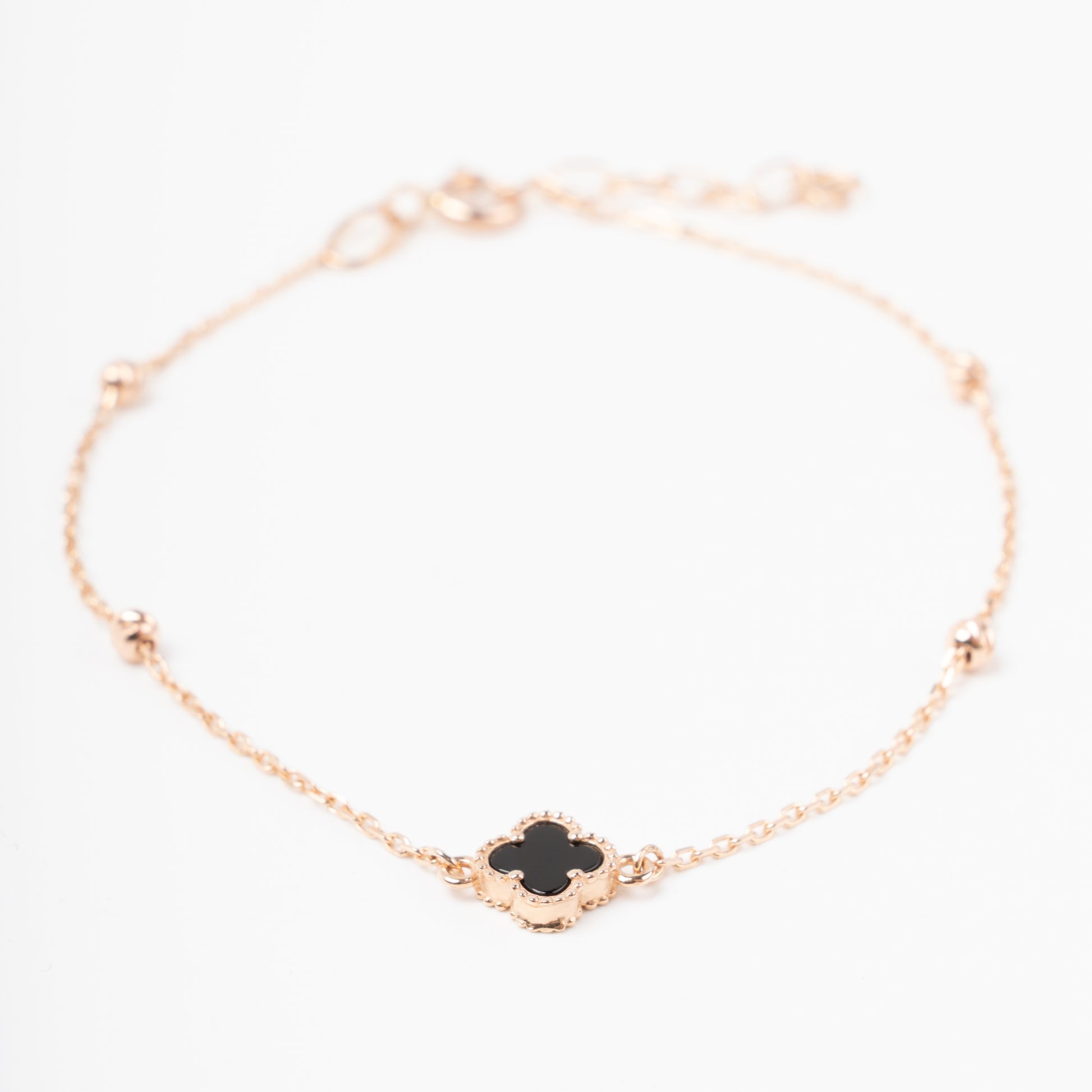 An exquisite 14K (585) Rose Gold bracelet featuring a black four-leaf clover centerpiece accented with four textured, cut-faced gold beads on a delicate chain with an adjustable clasp.