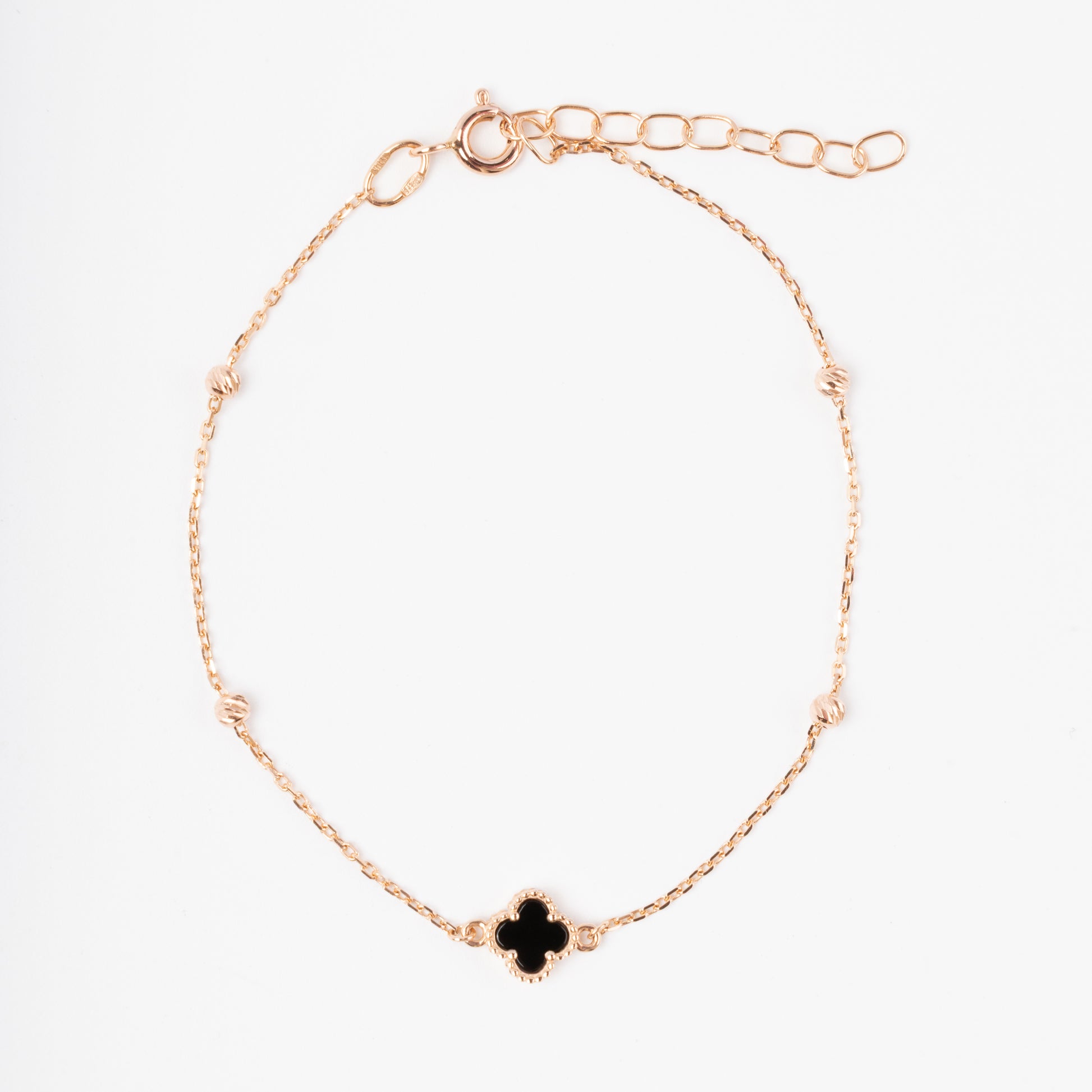 An exquisite 14K (585) Rose Gold bracelet featuring a black four-leaf clover centerpiece accented with four textured, cut-faced gold beads on a delicate chain with an adjustable clasp.