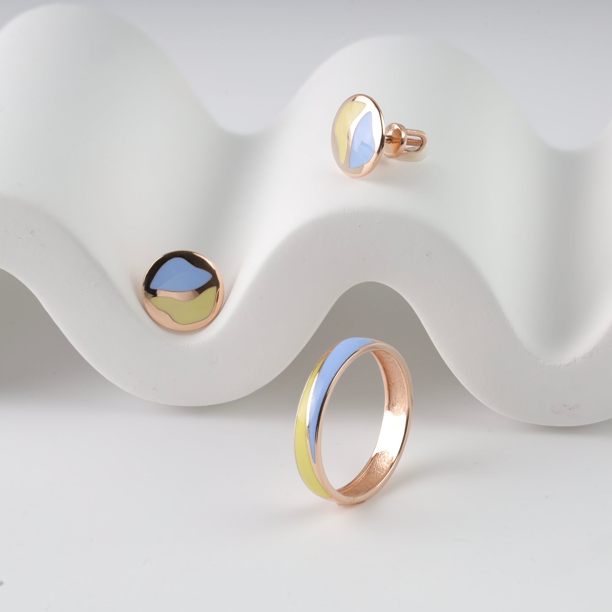 Sophisticated 14K (585) Rose Gold patriotic jewelry set featuring a minimalist wavy enamel ring and matching round stud earrings with vibrant blue and yellow accents, elegantly displayed on a white wavy decorative prop.