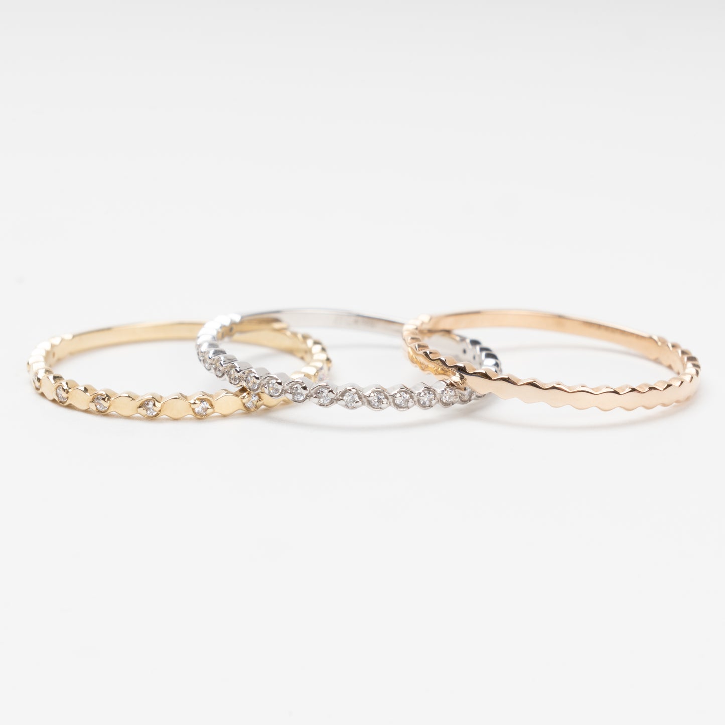 Sophisticated triple stackable ring set in 14K (585) multi-tone gold, featuring a central eternity band of clear zirconias White Gold between two uniquely scalloped Rose and Yellow Gold bands, displayed on a clean white background.