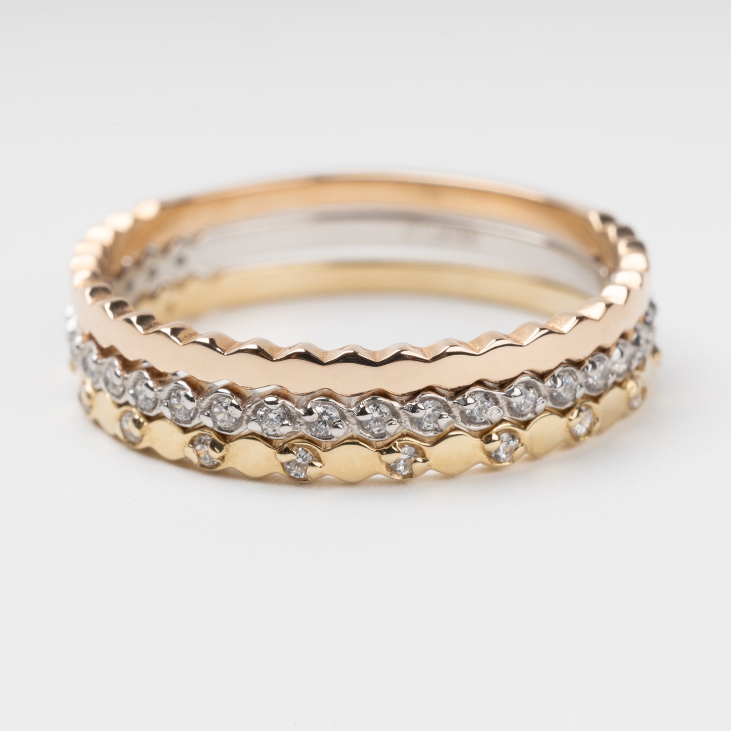 Sophisticated triple stackable ring set in 14K (585) multi-tone gold, featuring a central eternity band of clear zirconias White Gold between two uniquely scalloped Rose and Yellow Gold bands, displayed on a clean white background.